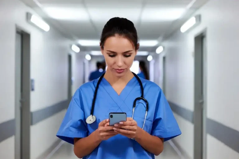 A nurse in scrubs reviewing shift options on a smartphone through the Clipboard Health platform