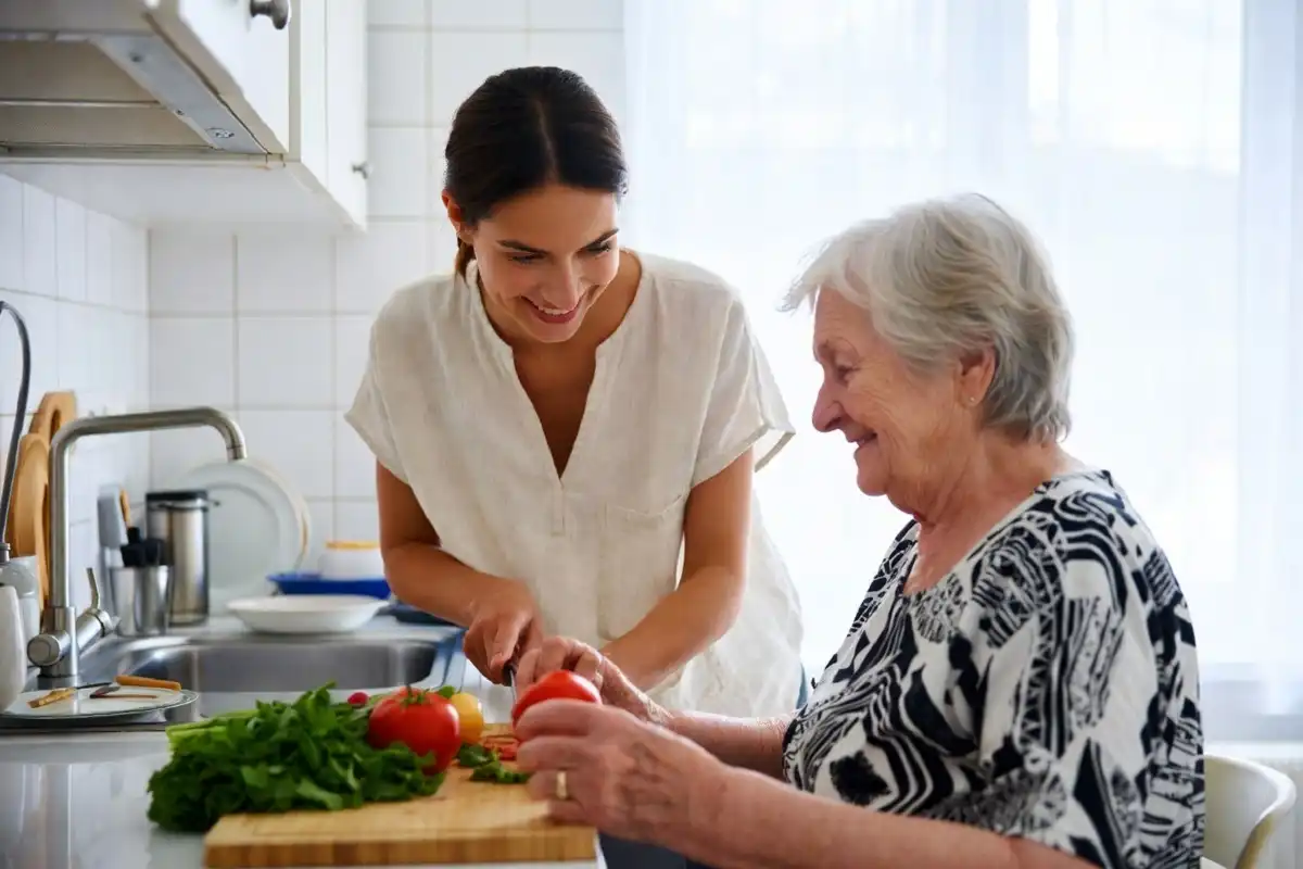 Caregiver helping an older woman prepare a healthy meal in her kitchen