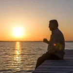Man sitting thoughtfully at sunrise during Men's Mental Health Month