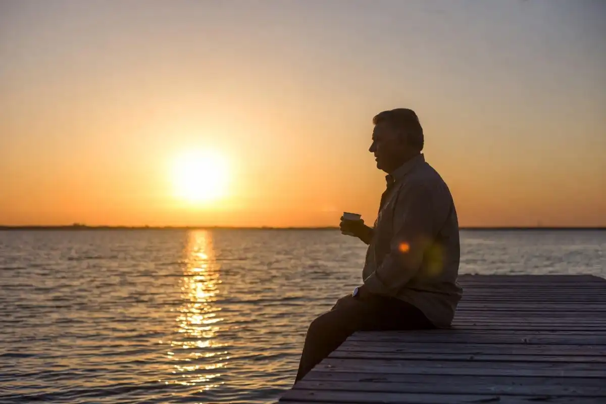 Man sitting thoughtfully at sunrise during Men's Mental Health Month