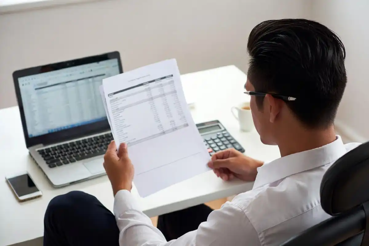 Business person analyzing quarterly earnings figures on financial documents